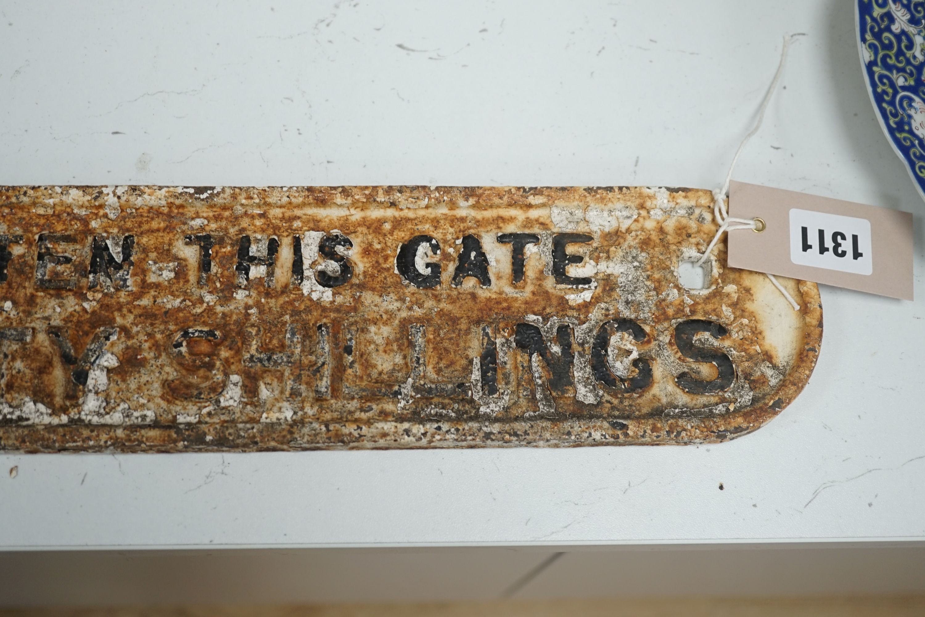 A cast iron gate sign, “any person who omits to shut and fasten this gate is liable to a penalty not exceeding forty shillings.”, 101 cms long.